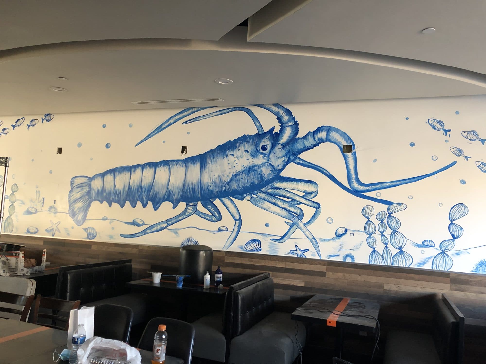 Large blue line-drawn crawfish mural above the booths at Clawszone in Garden Grove