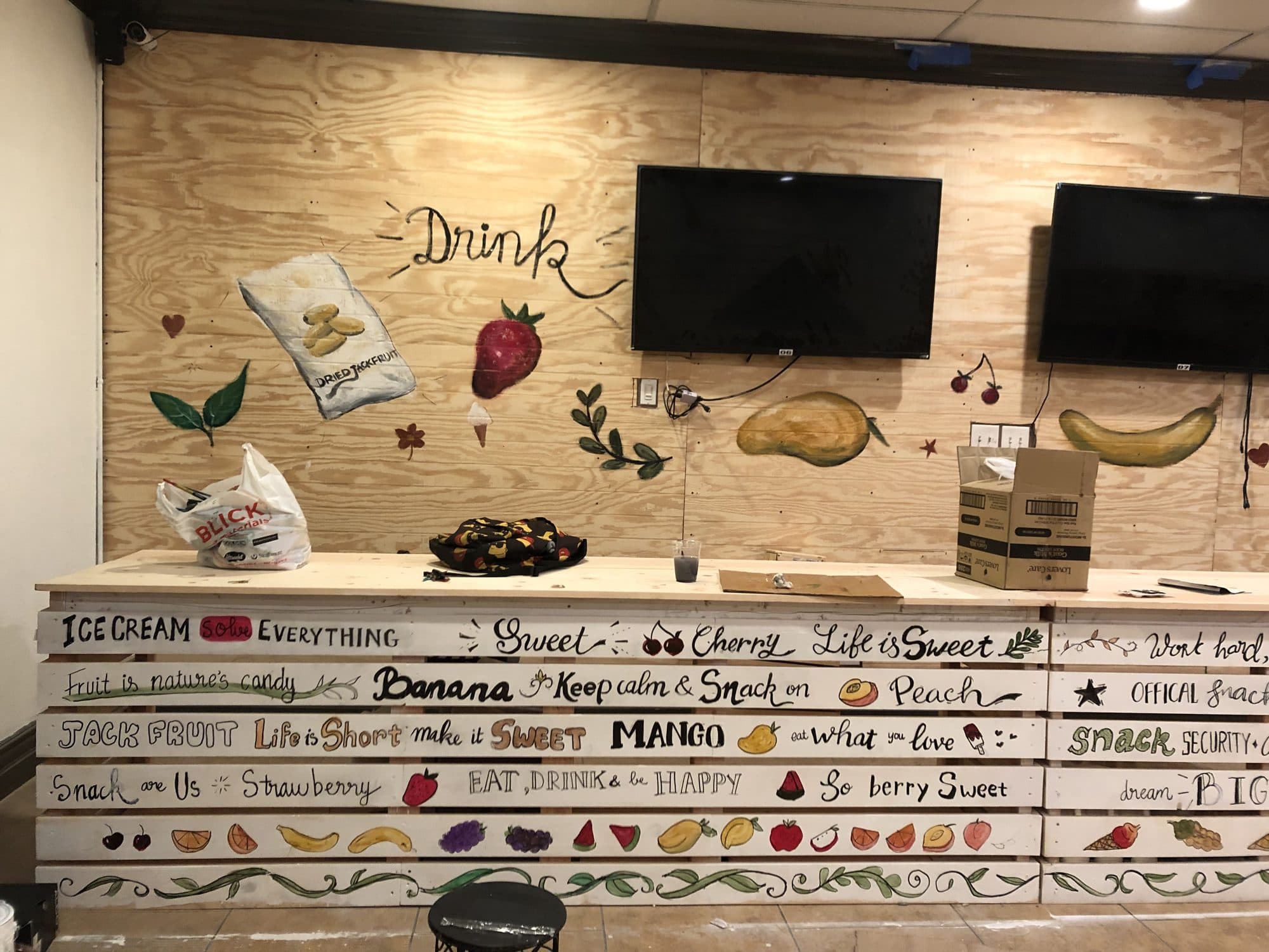 Hand-lettered fruit and drink words painted on a juice bar counter