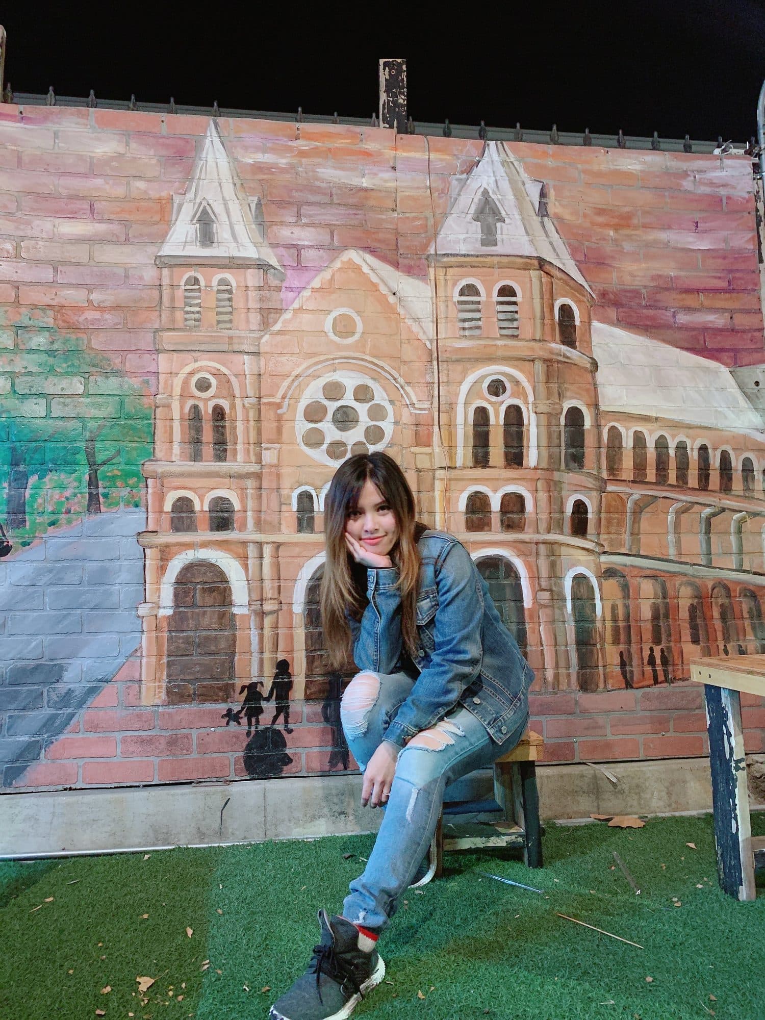 Eve Xa sitting in front of her mural of Saigon's Notre-Dame Cathedral