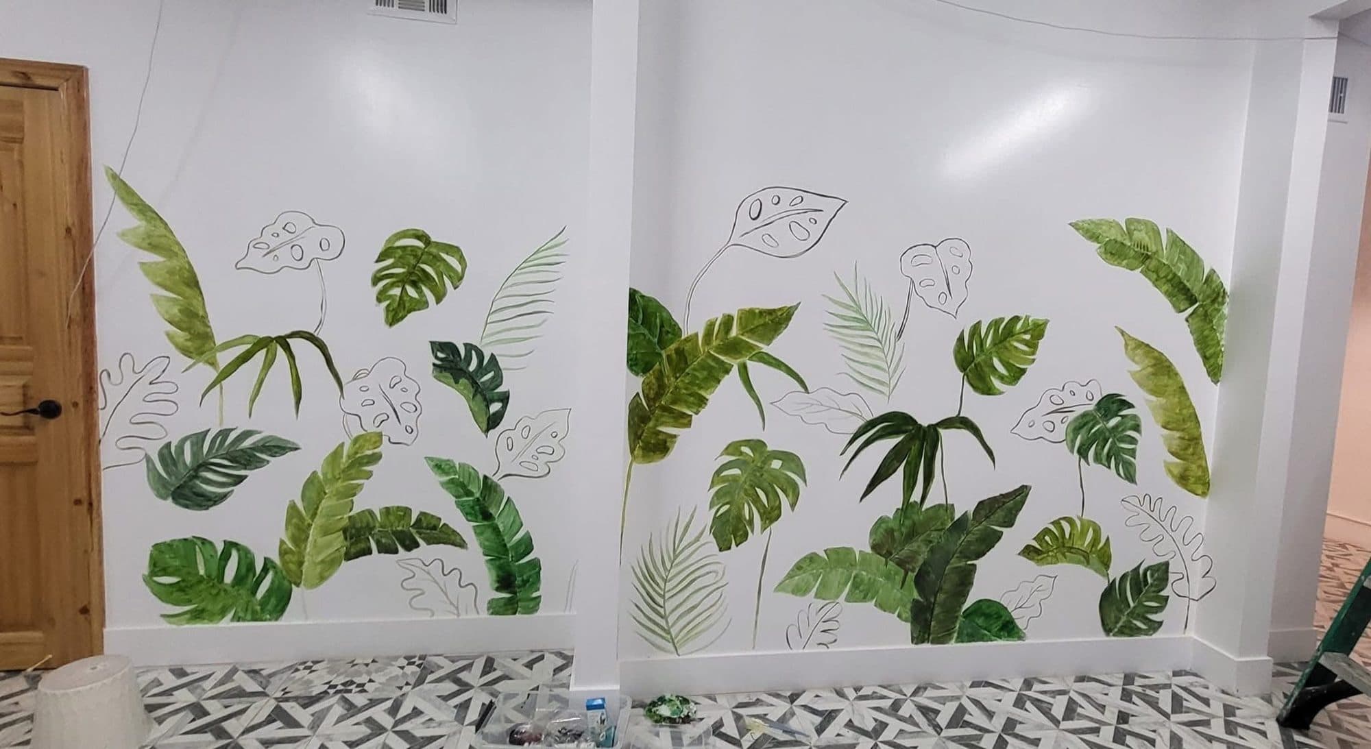 Wide botanical mural of green leaves and outlined flowers along a café wall