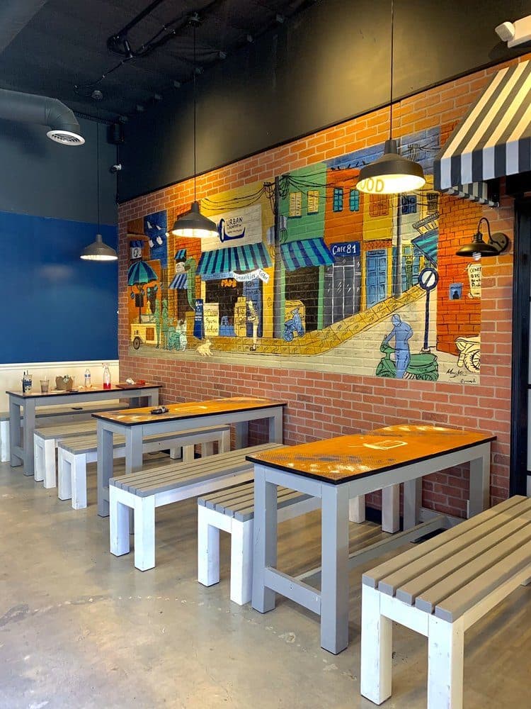 Mural of colorful Vietnamese shopfronts with awnings behind restaurant tables